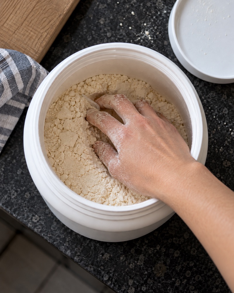 Hand wühlt in einer Proteindose nach dem Scoop
